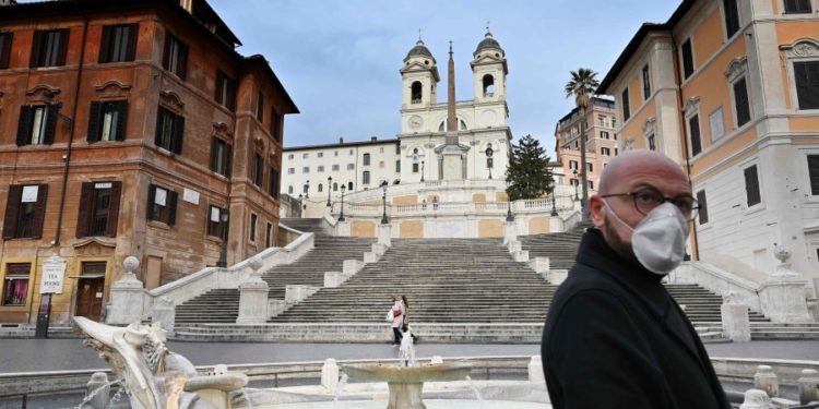 TOPSHOT - A man wearing a protection mask walks by the Spanish Steps at a deserted Piazza di Spagna in central Rome on March 12, 2020, as Italy shut all stores except for pharmacies and food shops in a desperate bid to halt the spread of a coronavirus. (Photo by Alberto PIZZOLI / AFP)