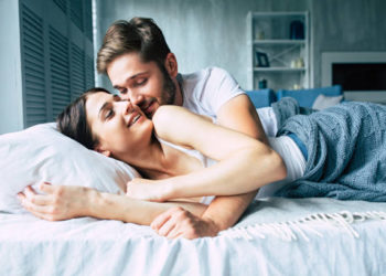Couple in bed at home are kissing each other