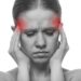 Woman having a migraine, isolated on white background, monochrome photo with red as a symbol for the hardening