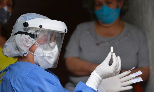 A health worker holds a resident's sample for a COVID-19 test, at the Kennedy neighborhood, one of the areas with more positive cases in Bogota, on June 3, 2020. (Photo by Raul ARBOLEDA / AFP) (Photo by RAUL ARBOLEDA/AFP via Getty Images)