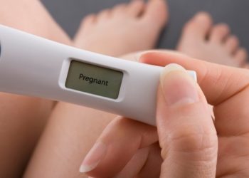 Woman taking a pregnancy test showing pregnant result