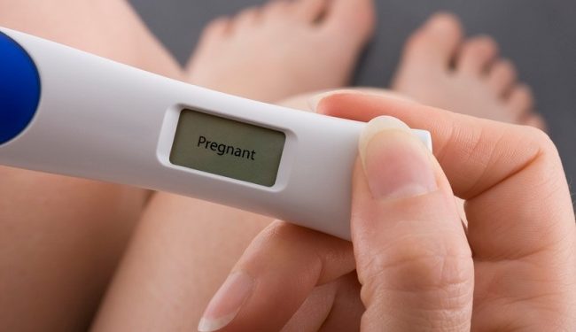 Woman taking a pregnancy test showing pregnant result