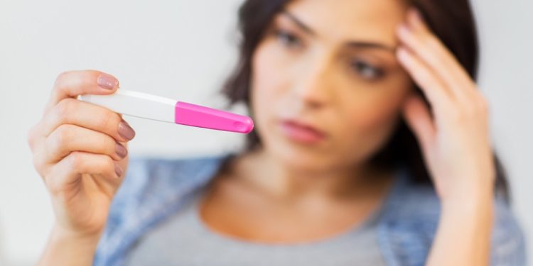 pregnancy, fertility, maternity and people concept - close up of sad unhappy woman looking at home pregnancy test