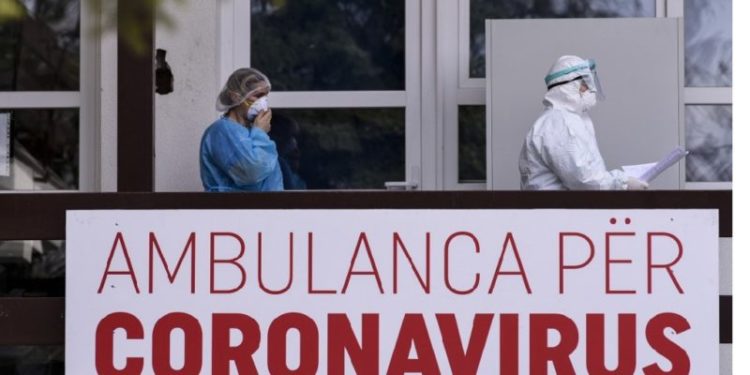 Members of the University Clinical Center of Kosovo in protective gear walk past a sign reading "Ambulance For Coronavirus" at the University Clinical Center of Kosovo in Pristina on March 14, 2020. - Kosovo reported its first coronavirus (COVID-19) case on March 13, 2020, in a 22-year-old Italian woman and a 77-year-old Kosovar man, both recently returned from Italy. (Photo by Armend NIMANI / AFP)