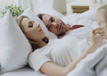Closeup of couple with relationship problems having emotional conversation while lying in bedroom at home
