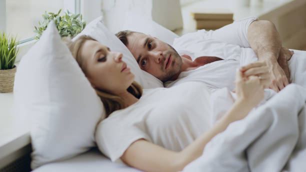 Closeup of couple with relationship problems having emotional conversation while lying in bedroom at home