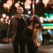 A smiling African American man and woman walk arm in arm on the streets of Chinatown in L.A. California on a warm evening, exploring the cities night life.  Bright traditional lanterns illuminate the scene.